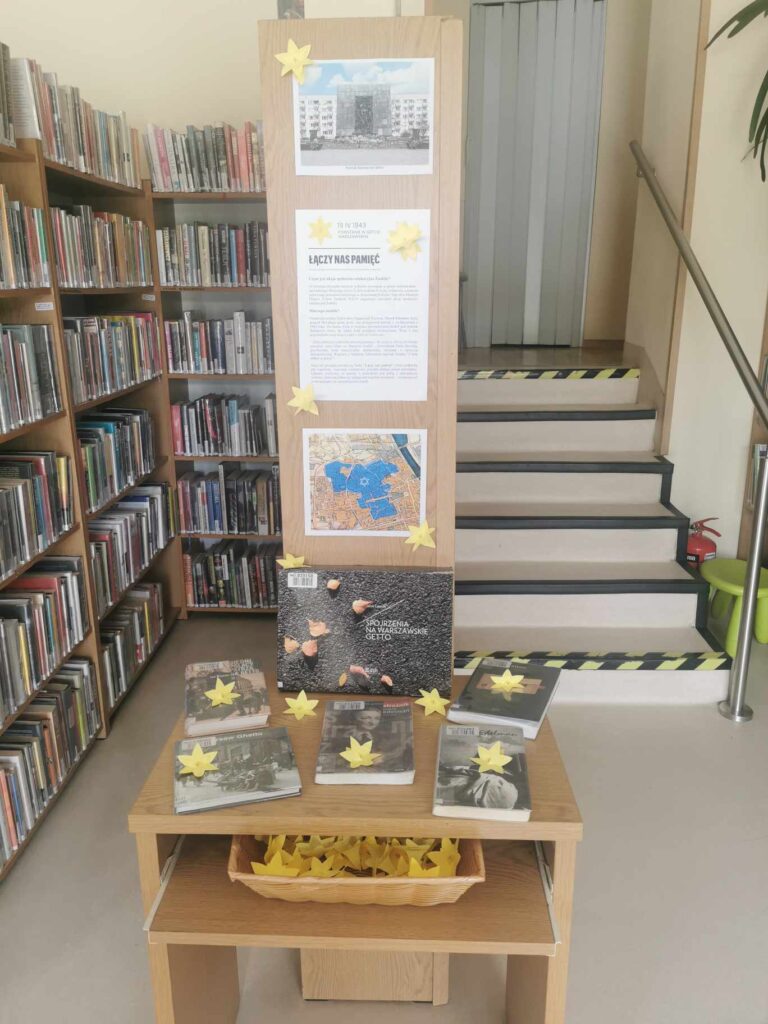 na stoliku w bibliotece są książki o powstaniu w getcie warszawskim, leżą na nich żonkile - symbole akcji
