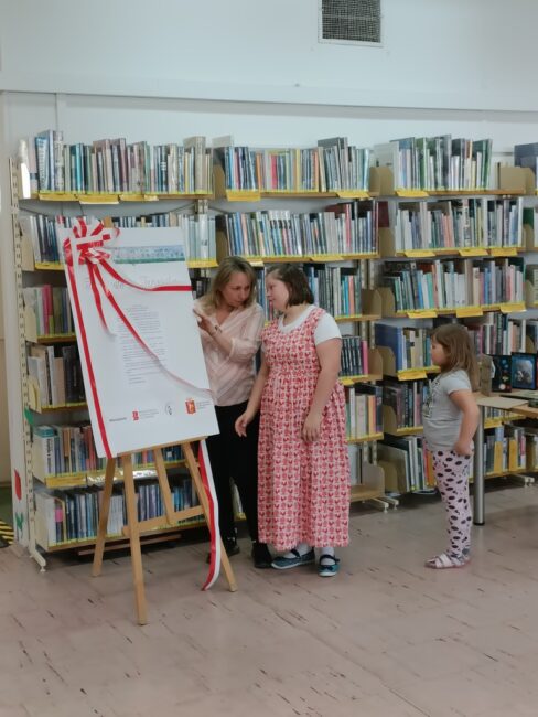 kierowniczka biblioteki uroczyście otwiera wystawę Tropiciele z Targówka wspólnie z uczennicą szkoły