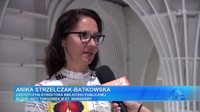 Zastępczyni dyrektora biblioteki publicznej na Targówku opowiada o Metrotece do mikrofonu; nagranie materiału dla programu Panorama TVP