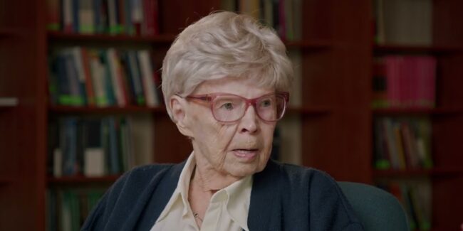 Halina Bieżan-Glonek, w tle regał z ksiażkami