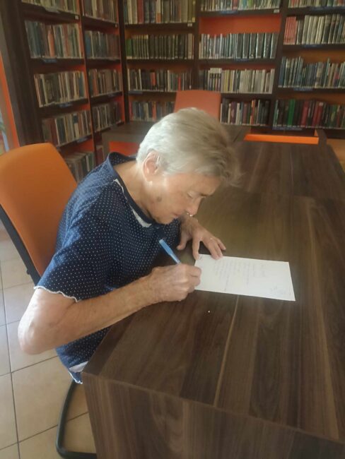 czytelniczka biblioteki odręcznie przepisuje wiersz Zbigniewa Herberta