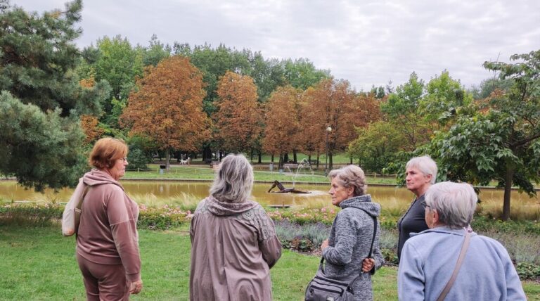kilkuosobowa grupa czytelników biblioteki spaceruje po parku rzeźby w parku bródnowskim