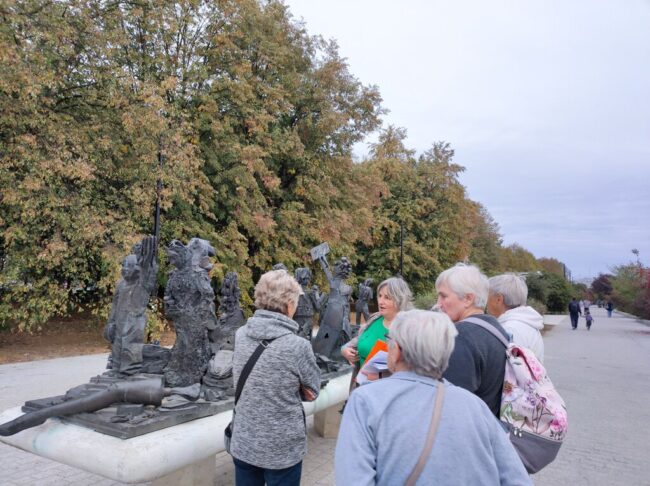 kilkuosobowa grupa czytelników biblioteki spaceruje po parku rzeźby w parku bródnowskim