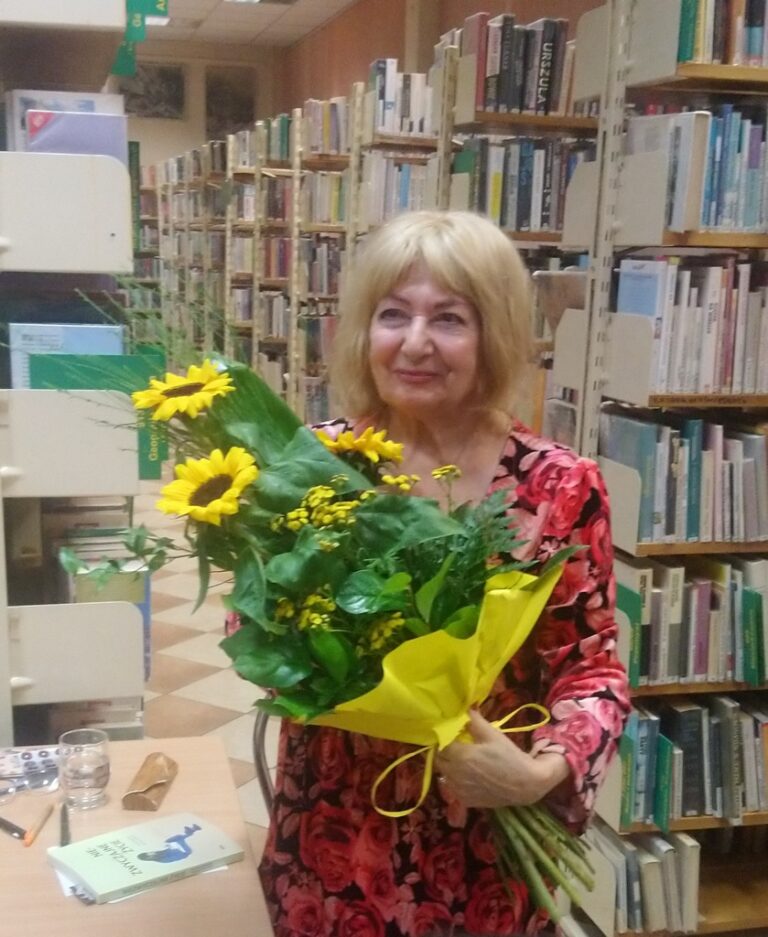 autorka pozuje do zdjęcia z kwiatami otrzymanymi od biblioteki