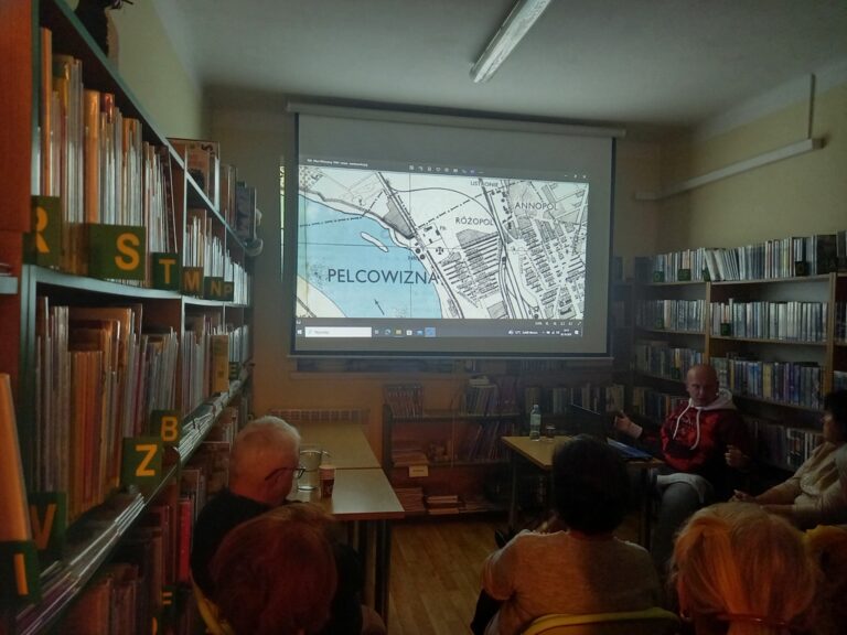 spotkanie varsavianistyczne; uczestnicy zapoznają się z prezentacją multimedialną wyświetlaną na ekranie projektora