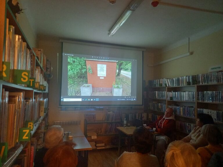 spotkanie varsavianistyczne; uczestnicy zapoznają się z prezentacją multimedialną wyświetlaną na ekranie projektora