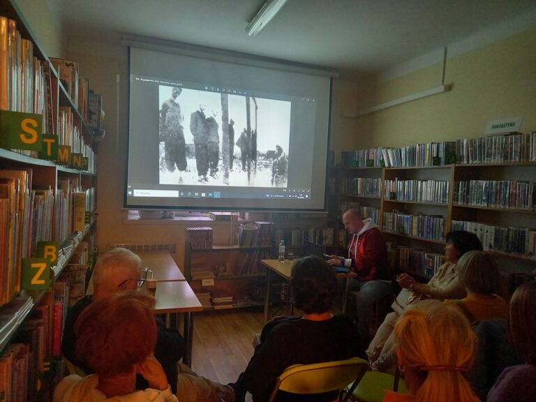 spotkanie varsavianistyczne; uczestnicy zapoznają się z prezentacją multimedialną wyświetlaną na ekranie projektora