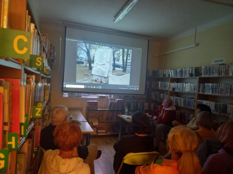 spotkanie varsavianistyczne; uczestnicy zapoznają się z prezentacją multimedialną wyświetlaną na ekranie projektora