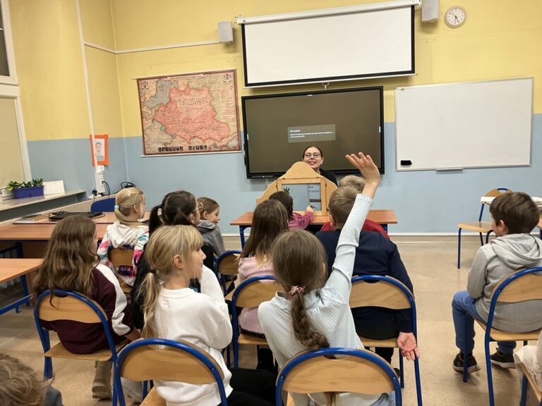 dzieci w sali lekcyjnej poznają bajkę prezentowaną w teatrzyku kamishibai