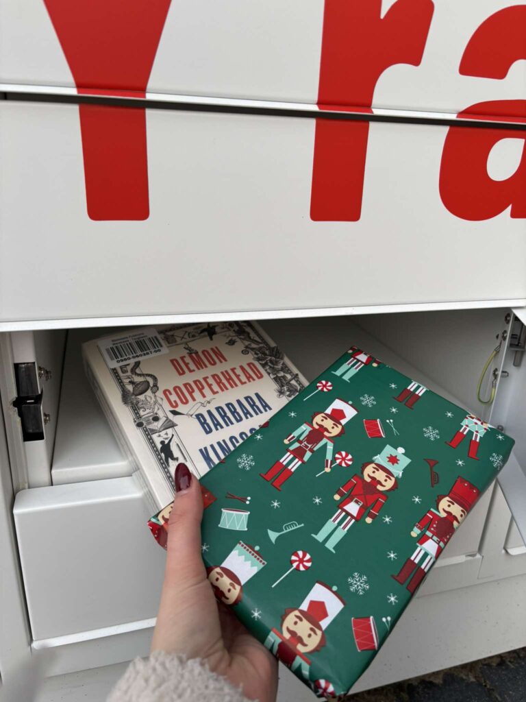 książka zapakowana w świąteczny papier ozdobny, wkładana do skrytki książkomatu