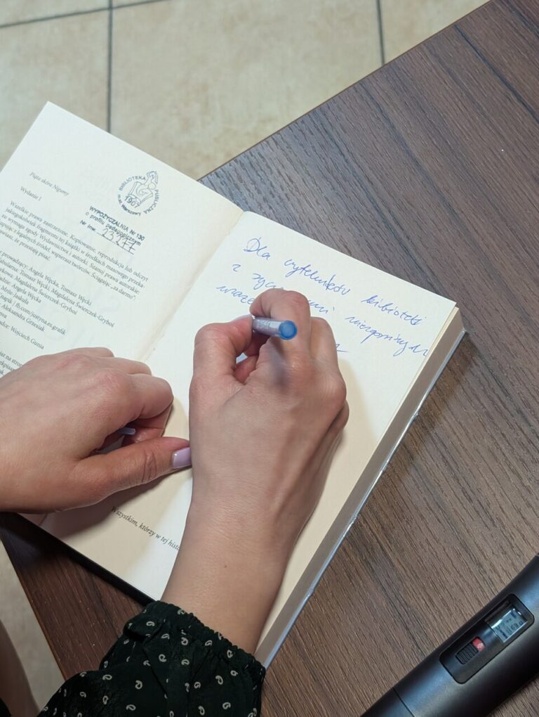 dłoń pisząca po książce