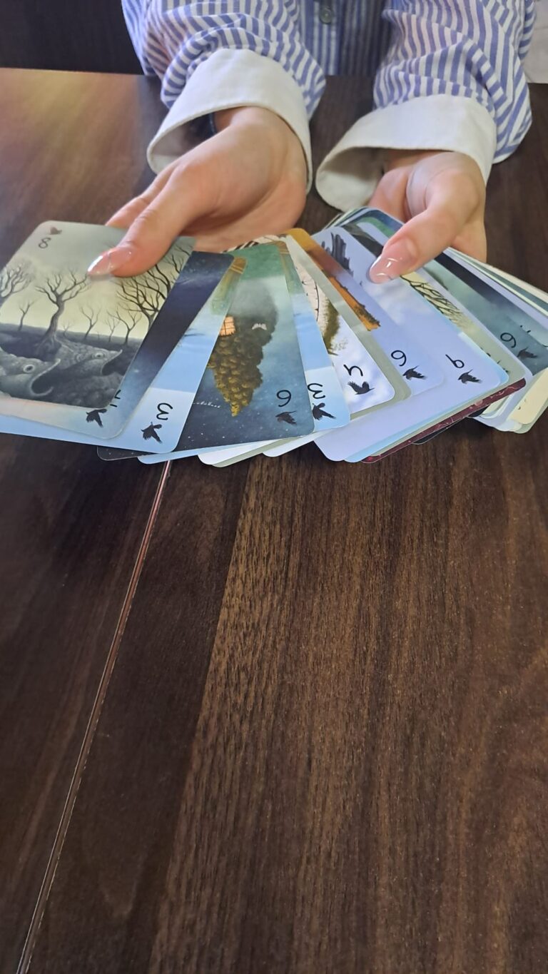 karty z gry Sen trzymane w dłoniach