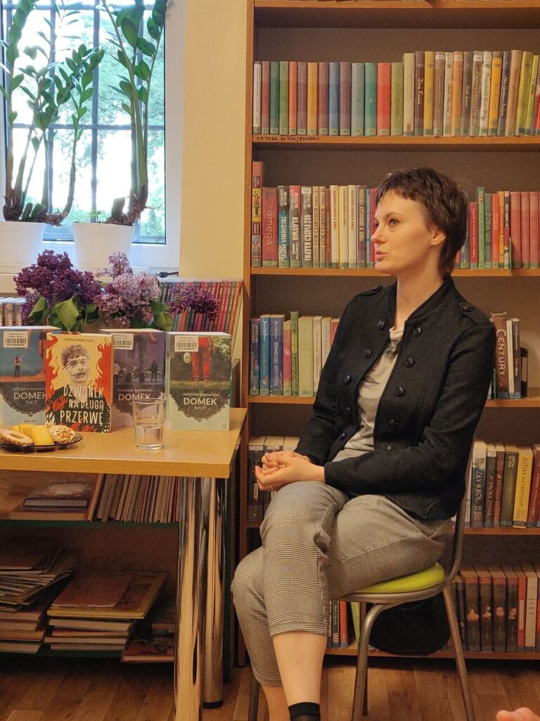 dwie kobiety siedzą przy stole podczas spotkania autorskiego