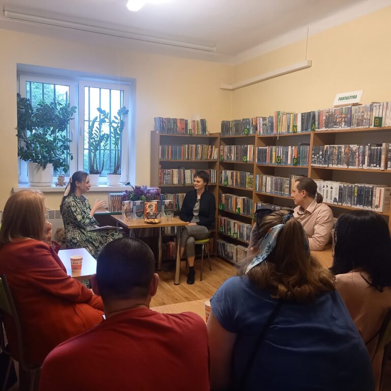 dwie kobiety siedzą przy stole podczas spotkania autorskiego