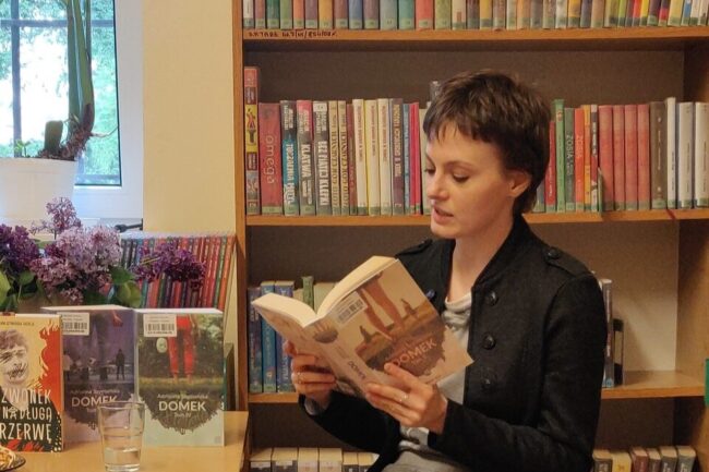 dwie kobiety siedzą przy stole podczas spotkania autorskiego