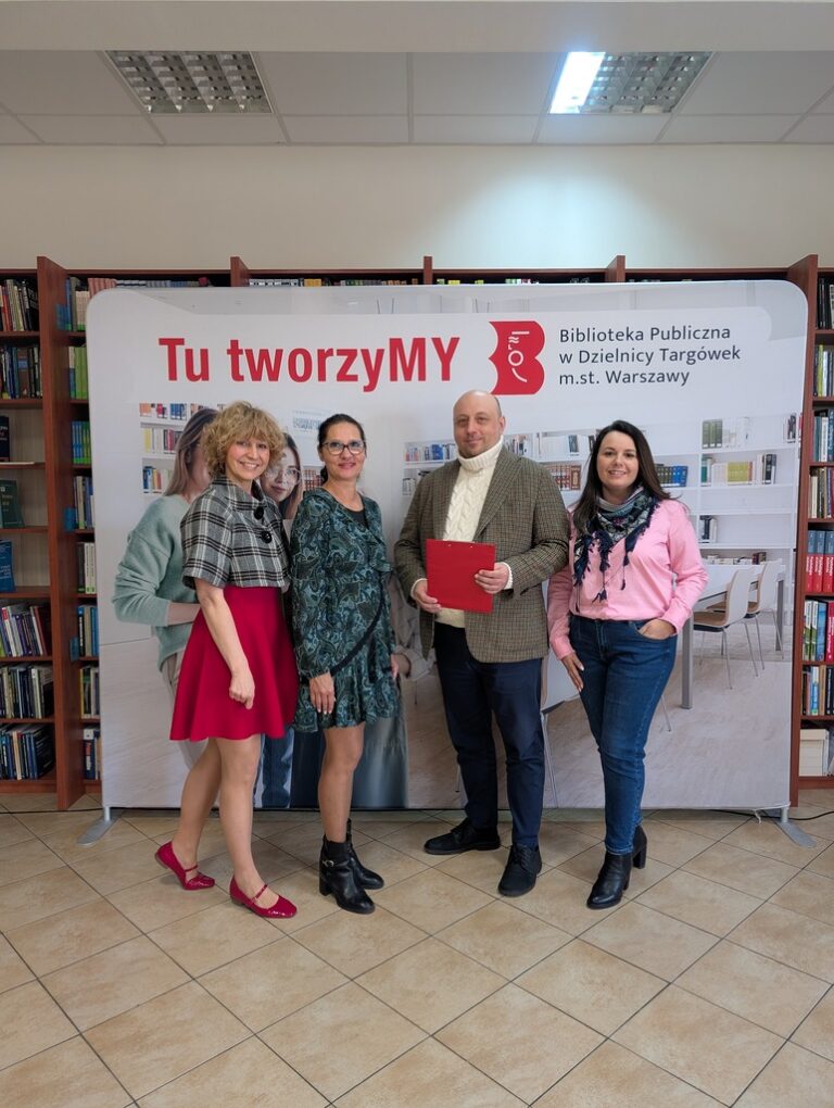 załoga biblioteki pozuje do zdjęcia na tle bannera z napisem Tu tworzymy