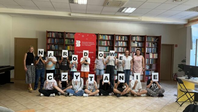 uczniowie szkoły podstawowej czytają w bibliotece fraszki Jana Kochanowskiego
