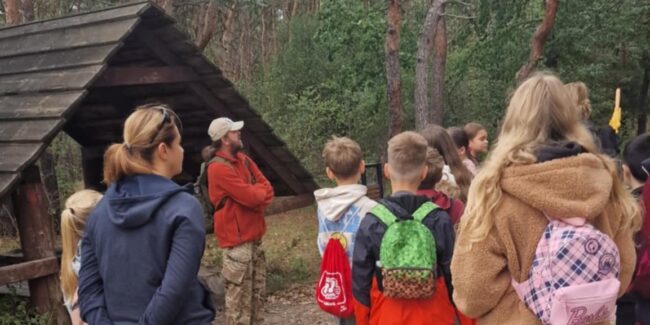 przewodnik oprowadza dzieci po lesie bródnowskim