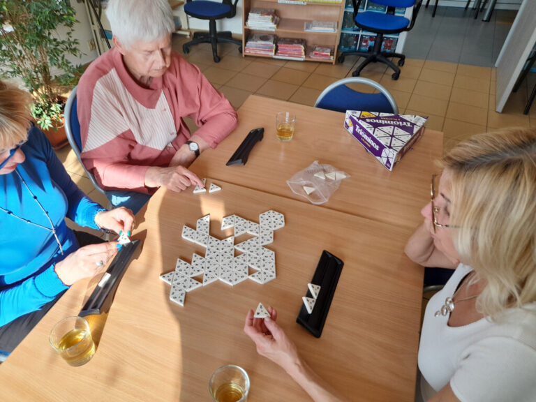 trzy osoby grają w gry Triominos i Rummikub