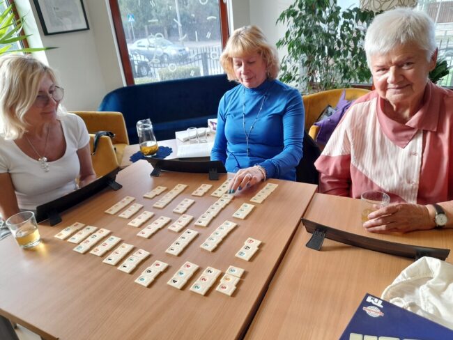 trzy osoby grają w gry Triominos i Rummikub