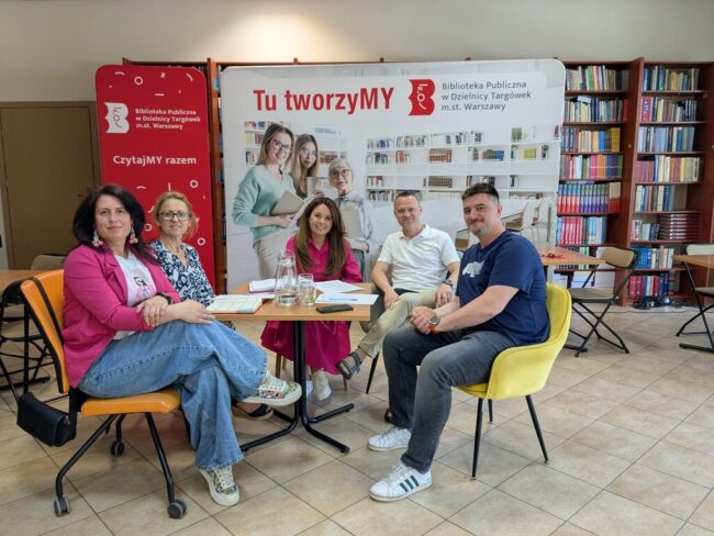spotkanie inaugurujące projekt pt. Wolontariat – Siła Pokoleń inspirowana historią; 5 osób siedzi przy stole i rozmawia w bibliotece