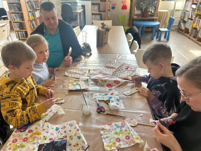 dzieci i dorośli tworzą zakładki do książek w bibliotece