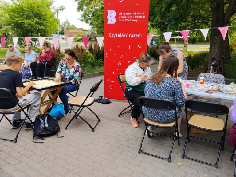 impreza plenerowa przed Czytelnią; dużo ludzi bierze udział w warsztatach decoupage i gra w bilard indyjski - carrom