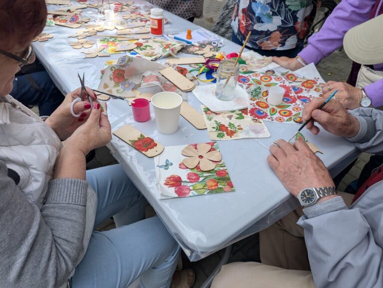 impreza plenerowa przed Czytelnią; dużo ludzi bierze udział w warsztatach decoupage i gra w bilard indyjski - carrom