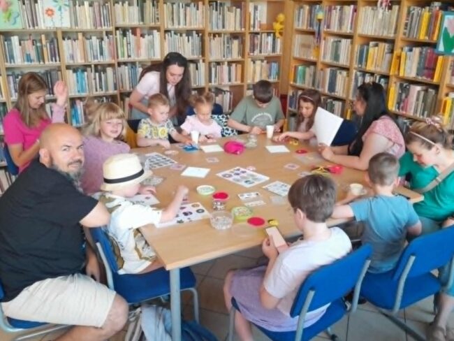 dzieci z rodzicami w bibliotece podczas zajęć kreatywnych