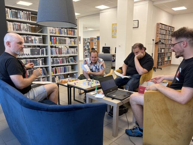 kilka osób siedzi przy stoliku w bibliotece - trwa sesja RPG