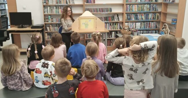 bibliotekarka prezentuje dzieciom bajkę w teatrzyku kamishibai